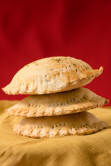 Nigerian pies stacked on a red and mustard background