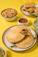 Meat pies, sausage rolls, and nuts against a mustard background © Cavan
