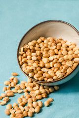 Nuts falling out of a bowl against bright blue