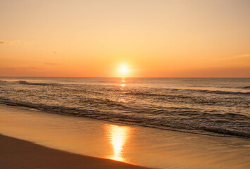 Obraz premium Golden sunset over calm ocean waves