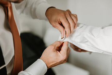 Groom fastening cufflinks, wearing a copper-colored tie