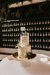 Elegant wedding cake with greenery, topped with acrylic signage