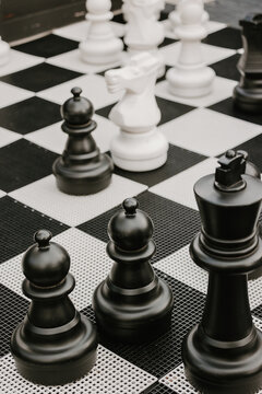 Giant black and white chess pieces on a checkered outdoor board