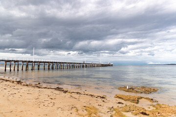 Obraz premium Point Lonsdale Pier stretching out into calm ocean under a cloudy sky