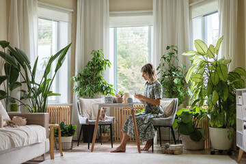 Young beautiful girl in a dress sits at a round white table and crochets. 