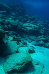 Deeper seabed, rocks and seascape in the blue water. Seabed with stones, underwater photography from scuba diving. Undersea empty calm landscape, adventure scuba diving.