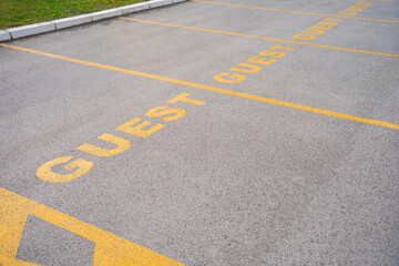 Fototapeta premium Reserved parking sign for Guest. Parking space with yellow painted sign of guests parking spot. Parking spot infront of corporation building or hotel.