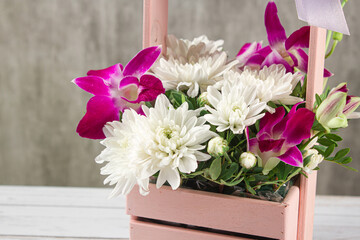 Bouquet of white flowers in a wooden pink basket. White chrysanthemums