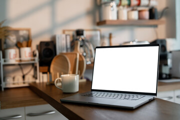 Open laptop with blank screen on a wooden desk in a kitchen room home office