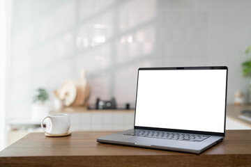 Fototapeta premium Open laptop with blank screen on a wooden desk in a kitchen room home office