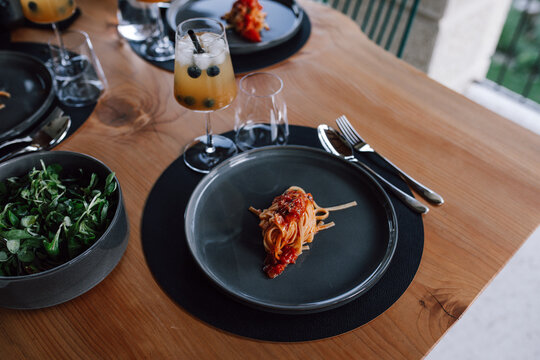 Elegant table setting with pasta, salad, and a cocktail drink