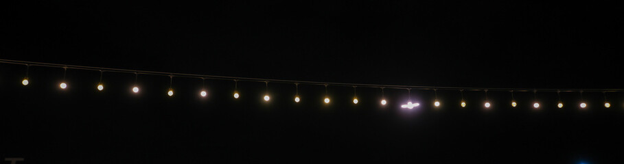 Decorative string lights hang on outdoor posts at night, commonly used for Christmas and other holidays.