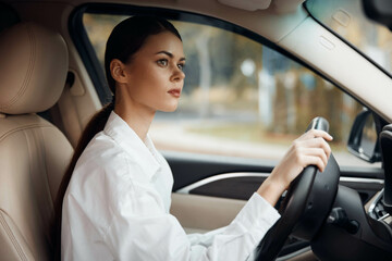 Woman driving car, hands on steering wheel, looking at camera