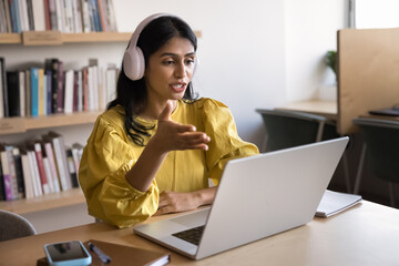 Serious young Indian online teacher giving webinar on Internet, online lesson, wearing headphones,...