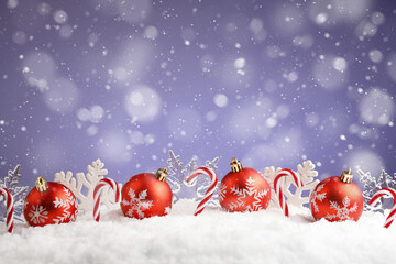 Vibrant red Christmas balls and snowflakes resting in snow