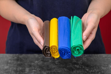 Kolorowe polietylenowe worki na śmieci w dłoniach, segregacja odpadów 