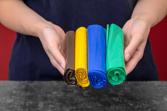 Kolorowe polietylenowe worki na śmieci w dłoniach, segregacja odpad&oacute;w 