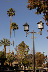 Bakersfield, California, USA - November 24, 2023: Afternoon sun shines on a historic downtown Bakersfield park, street lamps and autumn foliage.