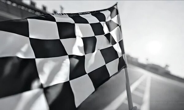 A black-and-white checkered flag waves in the wind, symbolizing victory, speed, and competition, set against a racing track backdrop.
