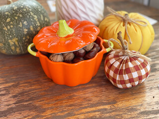Pot of nuts, chestnuts and pumpkins on wooden old table. Composition for Halloween holiday. Autumn...