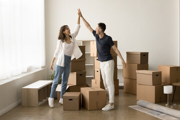 Successful new milestone. Excited young married couple renters tenants homeowners stand in living...