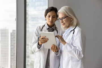 Young female doctor intern meet older age colleague ask question about patient history case show...