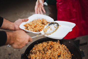 A person is handing over a delicious plate of food to another individual, sharing a moment of nourishment and care, showcasing the importance of meals in human connection