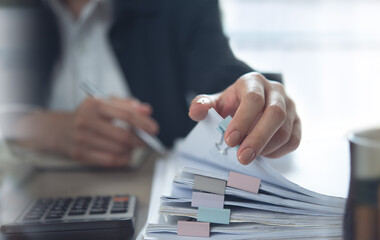 Document management. Businesswoman working with stack of paper files for searching and checking...