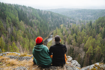 A group of friends is happily enjoying a serene overlook in a beautiful forest, soaking in the...
