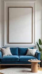 A modern living room interior with a blue velvet sofa featuring beige throw pillows. A large, blank canvas in a wooden frame hangs on the wall above the sofa. A wooden coffee table with books on top s