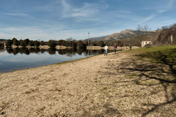 A boy rides his bicycle towards his mother along a path next to a lake