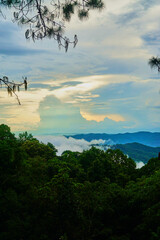 A beautiful mountain range with a cloudy sky and a few trees