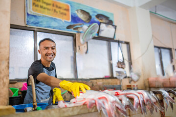 A happy fishmonger showcases fresh seafood at a vibrant, bustling market full of energy