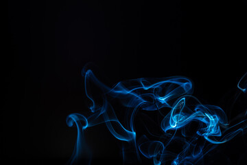 Blue smoke isolated on a black background. A thin curved line of smoke, steam from a burnt candle...