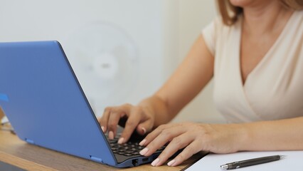 Fototapeta premium Woman working at laptop, focused and productive. Her hands move swiftly over laptop keyboard, showing efficiency. Ideal for themes like remote work, technology, and daily tasks with a laptop.