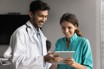 Two health care facility staff teammates young doctor and nurse discuss prescription plan for...