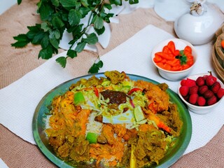 A plate of biryani with a bunch of food on it