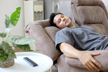 Tired Asian Man Sleep on Sofa While Watching TV	