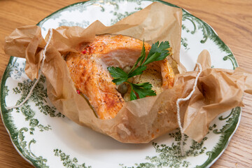 Salmon fillet and potatoes seasoned with herbs and spices being cooked in parchment paper
