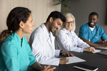 Friendly diverse doctors teammates glad to hire recruit new staff member on team meeting at...