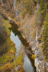 A stunningly beautiful river gently flows through a breathtaking scenic canyon, which is bordered by vibrant trees and rugged rocks, thereby creating a truly picturesque natural landscape