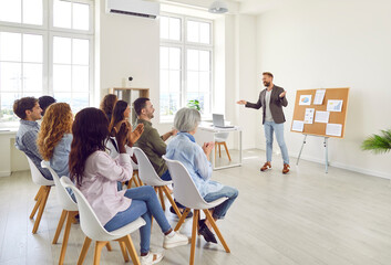Group of happy joyful business people applauding to speaker sitting on chairs in a meeting room....