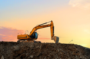 Excavator in open pit on sunset. Open-pit mining. Backhoe dig ground in quarry. Heavy machinery...