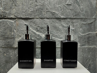 Black bottles of shower gel, shampoo and conditioner in the bathroom