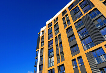 Fototapeta premium Modern facade building on blue sky. Skyscraper facade. Modern High rise residential facade. Windows of Skyscraper. Architecture building exterior, window house block. High Rise house background.