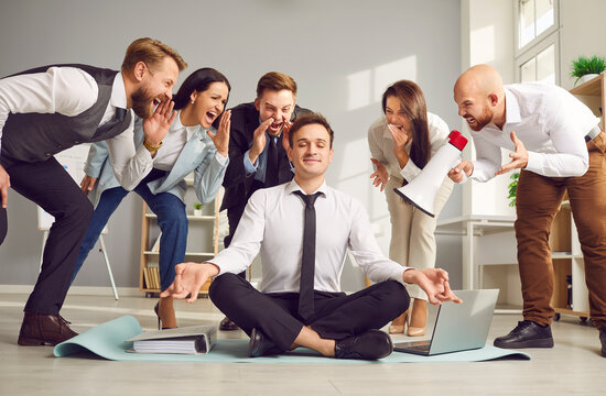 Serene businessman, meditates in the office, surrounded by shouting colleagues. Despite the chaos, focused on meditation, calm and relaxation, effectively ignoring the stress around.