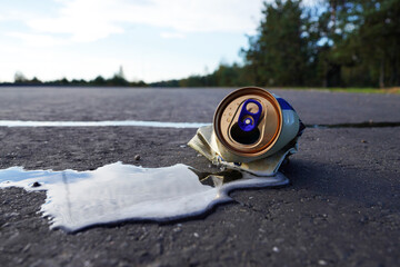 Crumpled beer can on asphalt with spilled alcohol. Discarded broken carbonated drink can on road. Problem social, crime. Food garbage, pollution, waste, Thrown out Crushed juce. Beer Can Crushed.