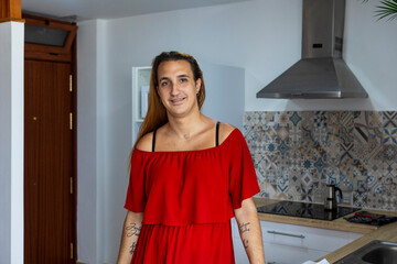 Trans woman in red dress standing in a modern kitchen