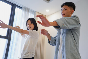 Two young Asian people dancing at home