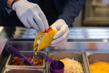 Worker preparing Mexican tacos on food counter in fast food restaurant